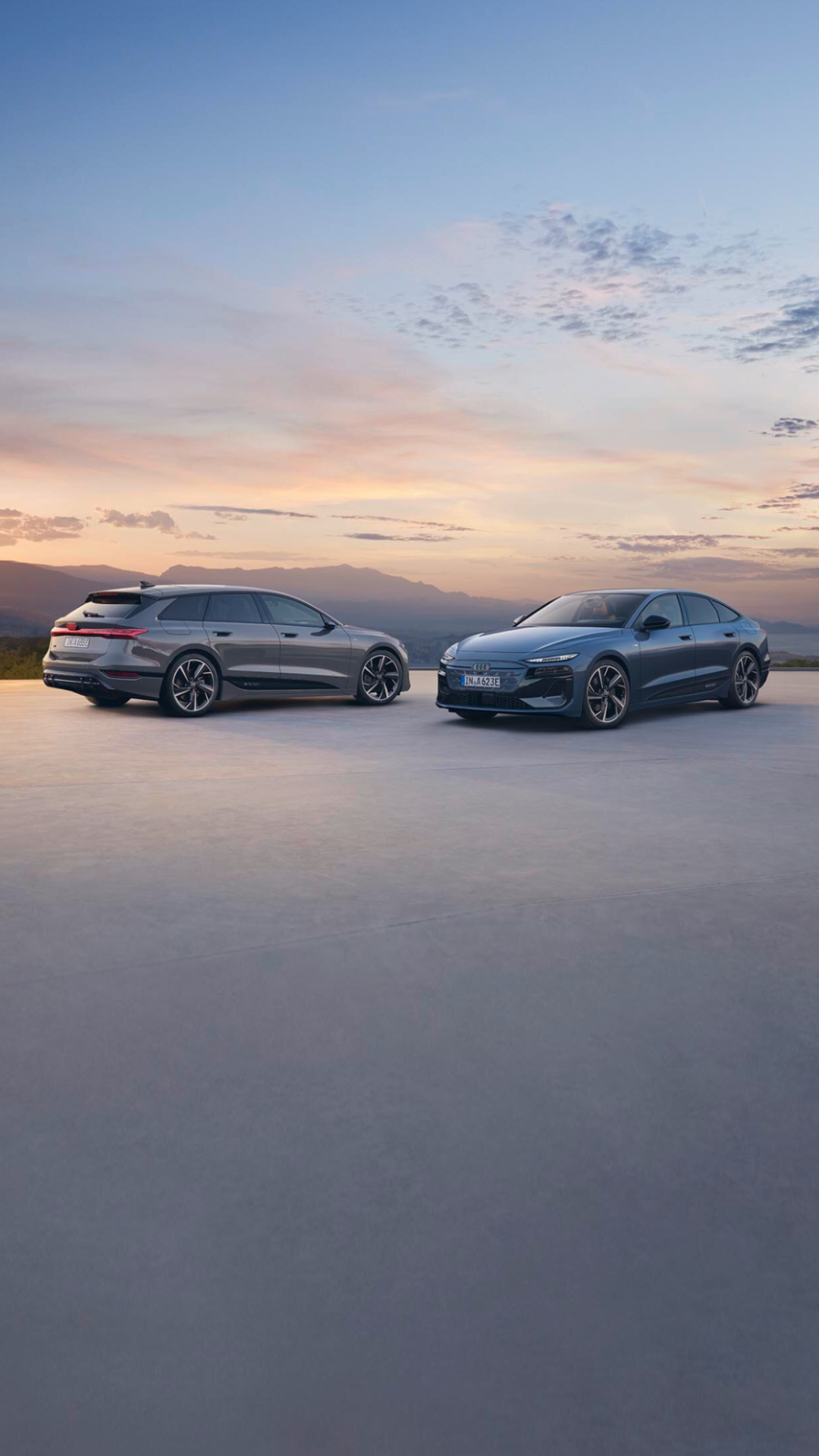 Dwa samochody Audi stojące obok siebie z pięknym niebem z tyłu